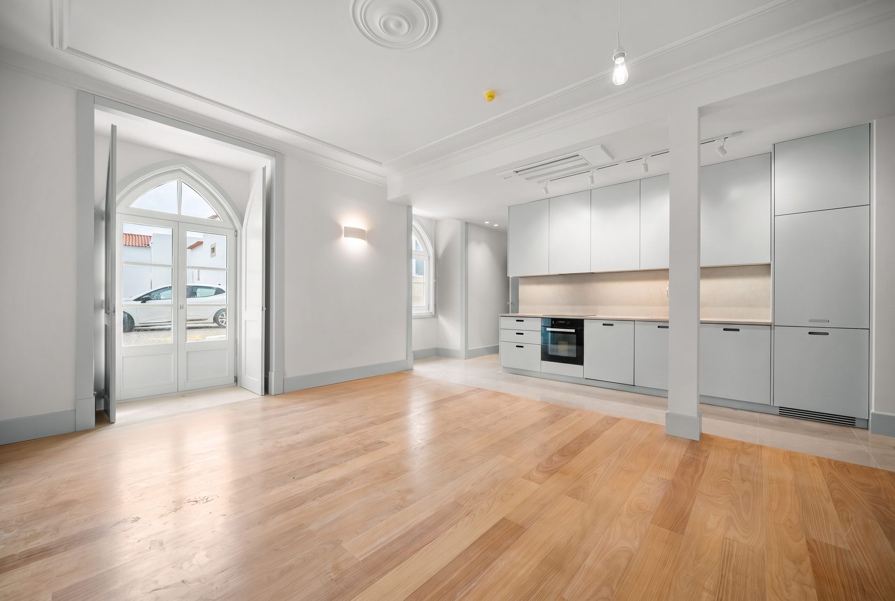 Casa da Coroa T1 — living room and kitchen with the arched door