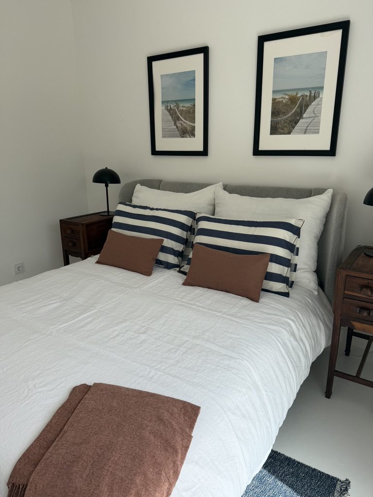 Vale da Rosa, Estoi — double bedroom with a grey upholstered headboard and framed coastal prints
