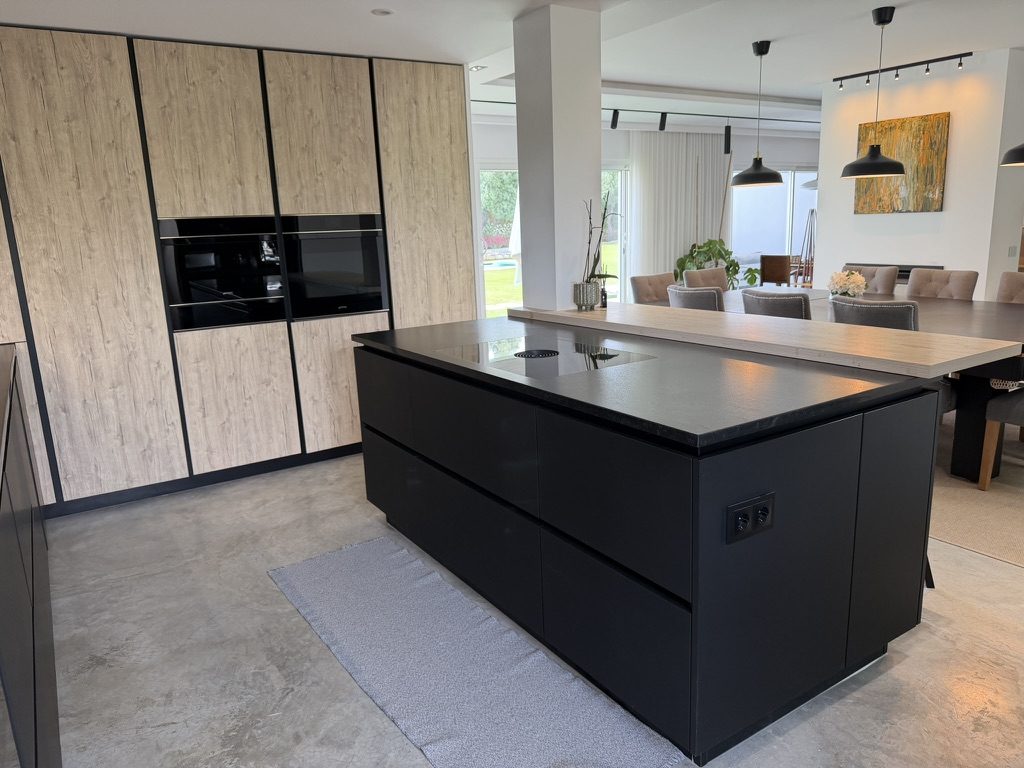Vale da Rosa, Estoi — main kitchen with a matte-black island, induction hob and integrated oak units, open to the dining area