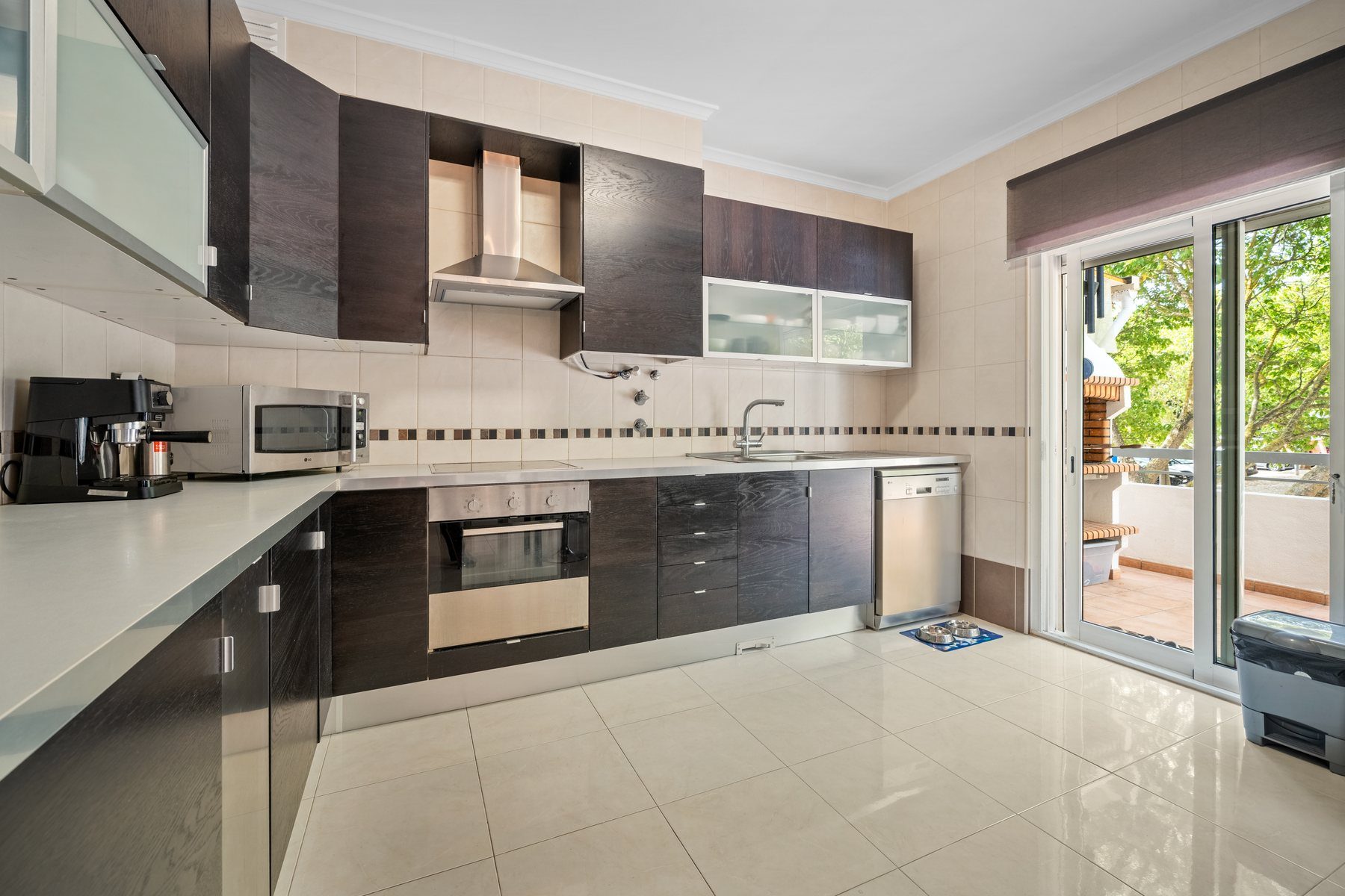 Fitted kitchen with dark cabinetry opening to the terrace