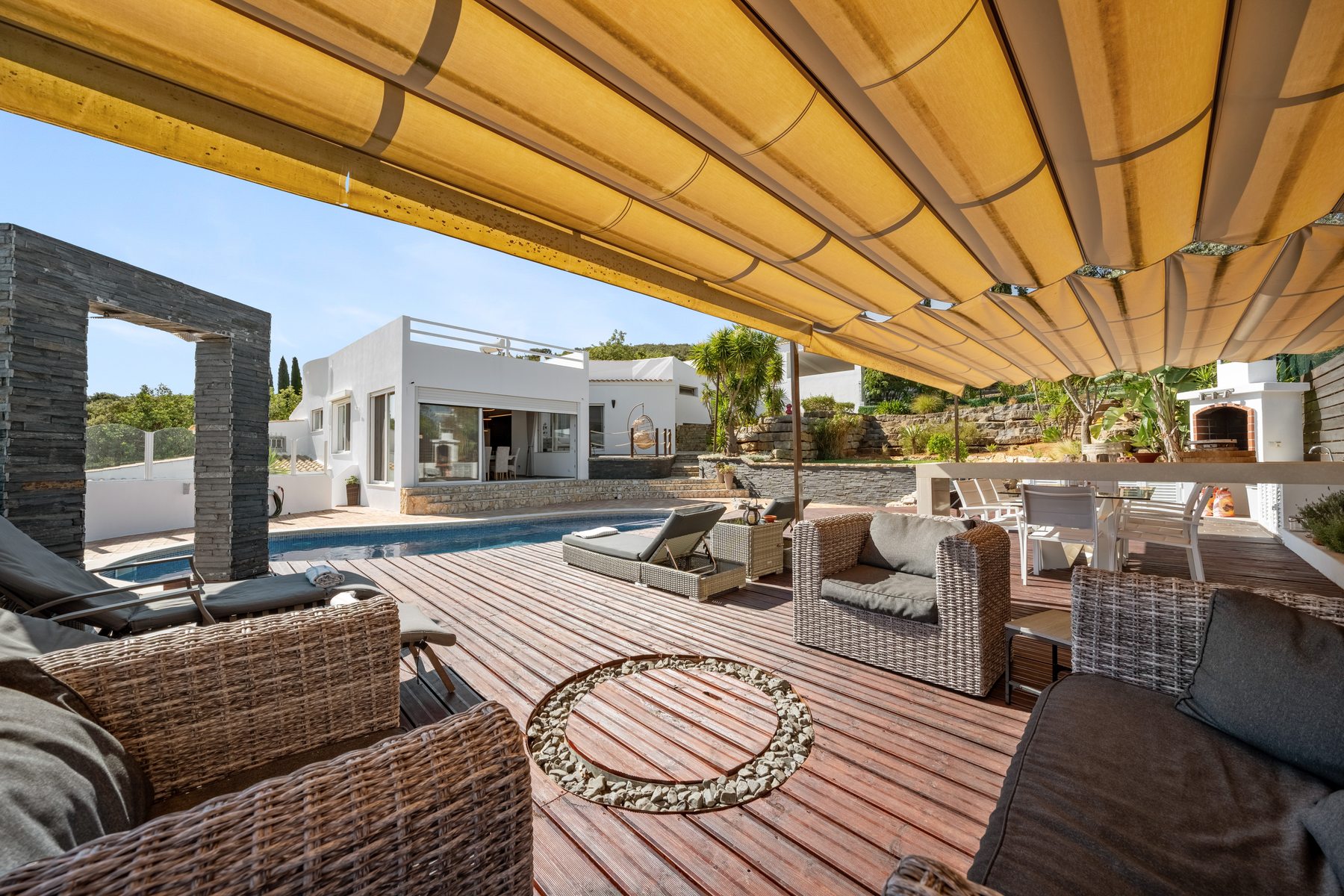 Covered outdoor lounge under a retractable roof beside the pool